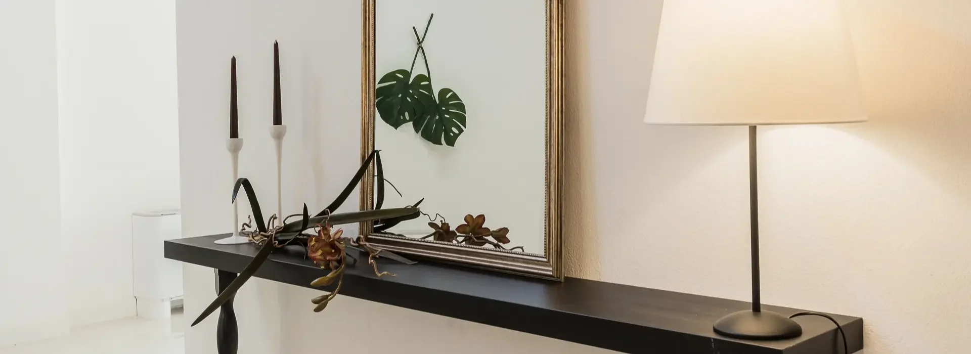 mobile di fronte allo specchio con una pianta e una lampada accesa