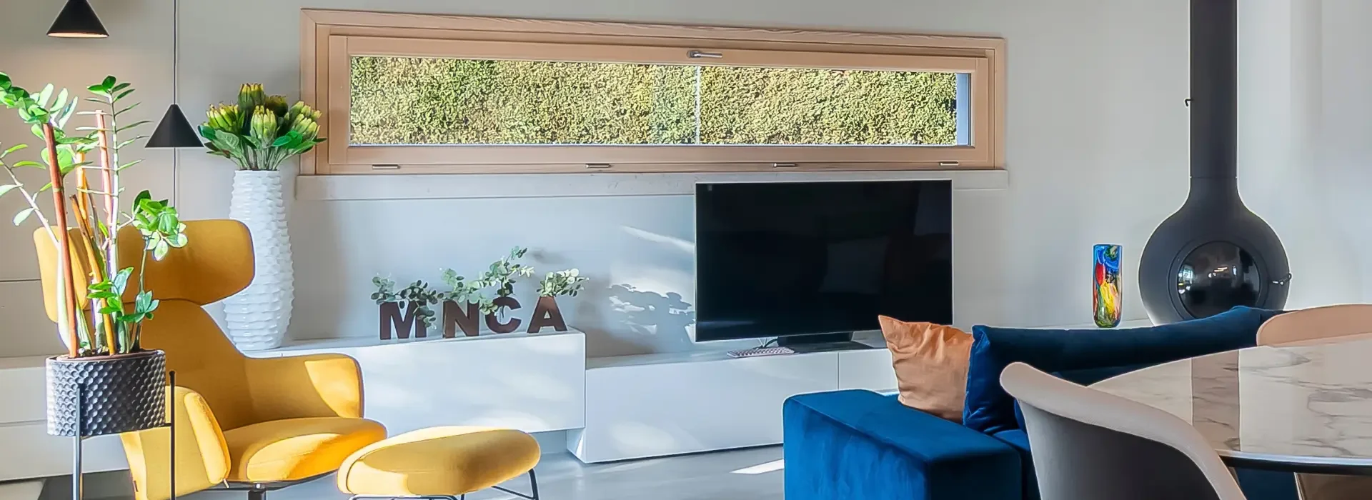 salotto con vista su tv, divano blu, ampia finestra con vista su piante